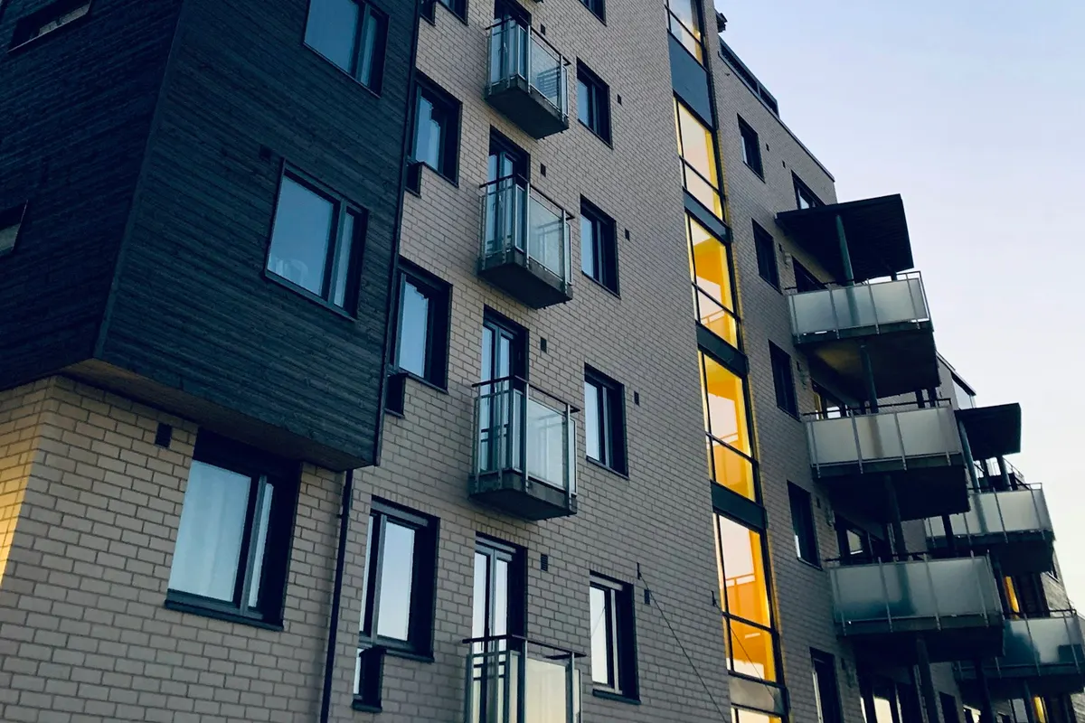 Edificio residencial contemporáneo de ladrillo claro, con balcones y grandes ventanales.