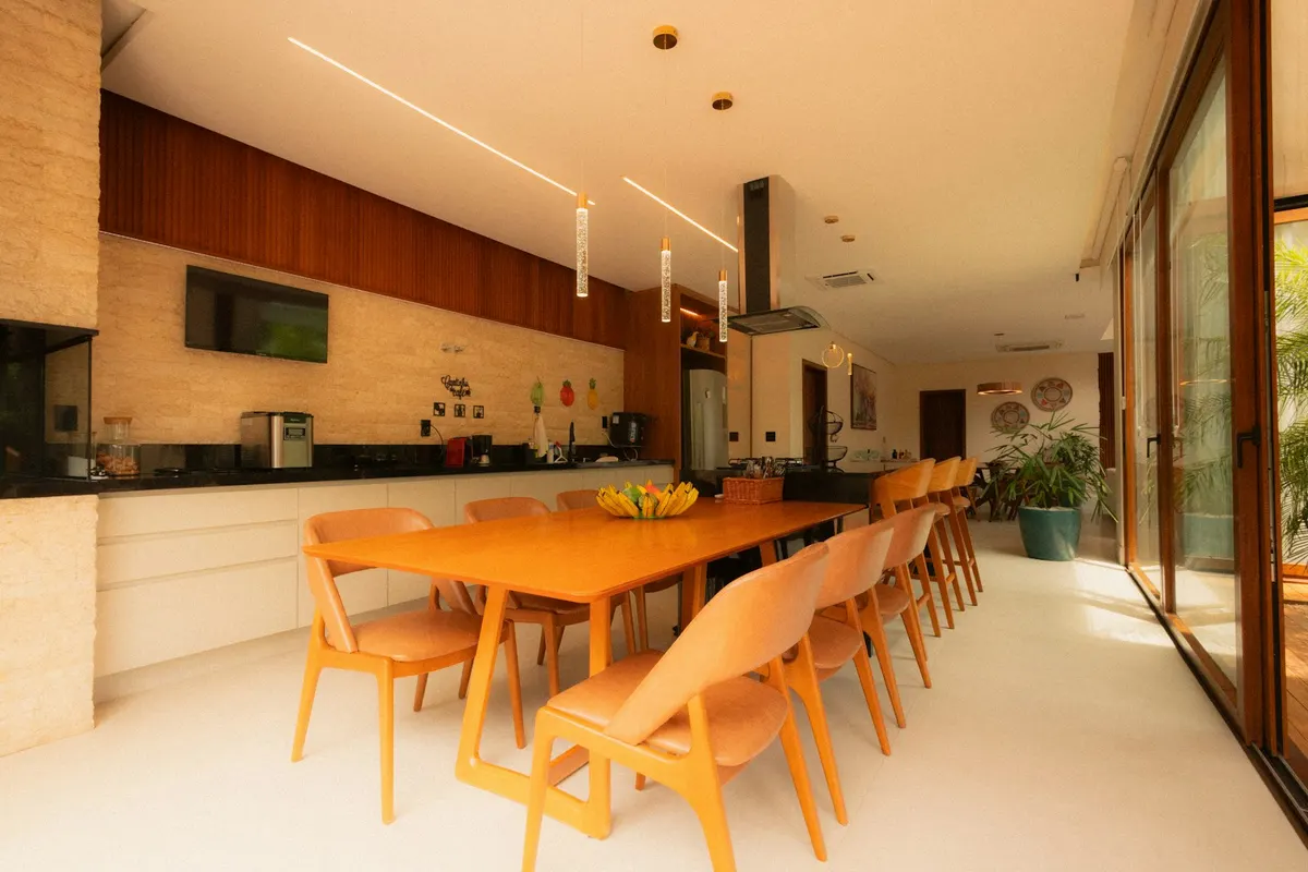 Shared kitchen and dining area, with a long wooden table and glazing looking outside.